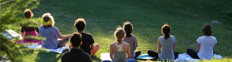 Groupe assis en méditation sur une pelouse ensoleillée