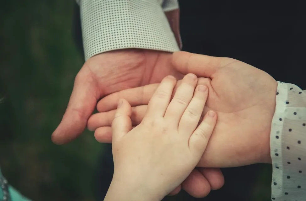 Trois mains superposées, adulte, jeune et enfant