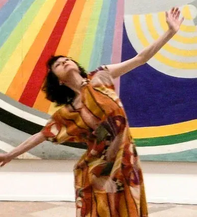 Danseuse en robe colorée devant une peinture en arcs colorés