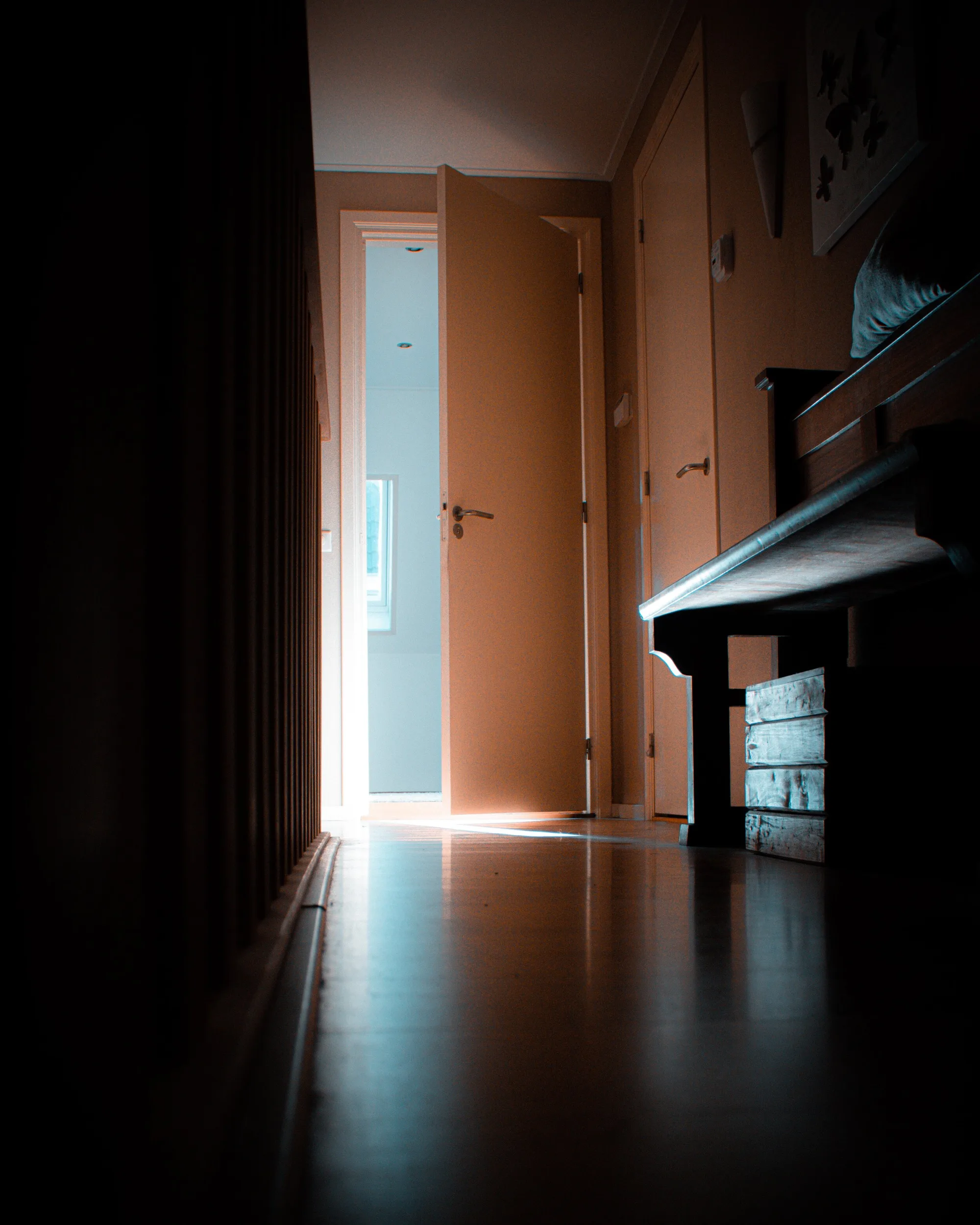 Couloir sombre et porte entrouverte laissant passer la lumière