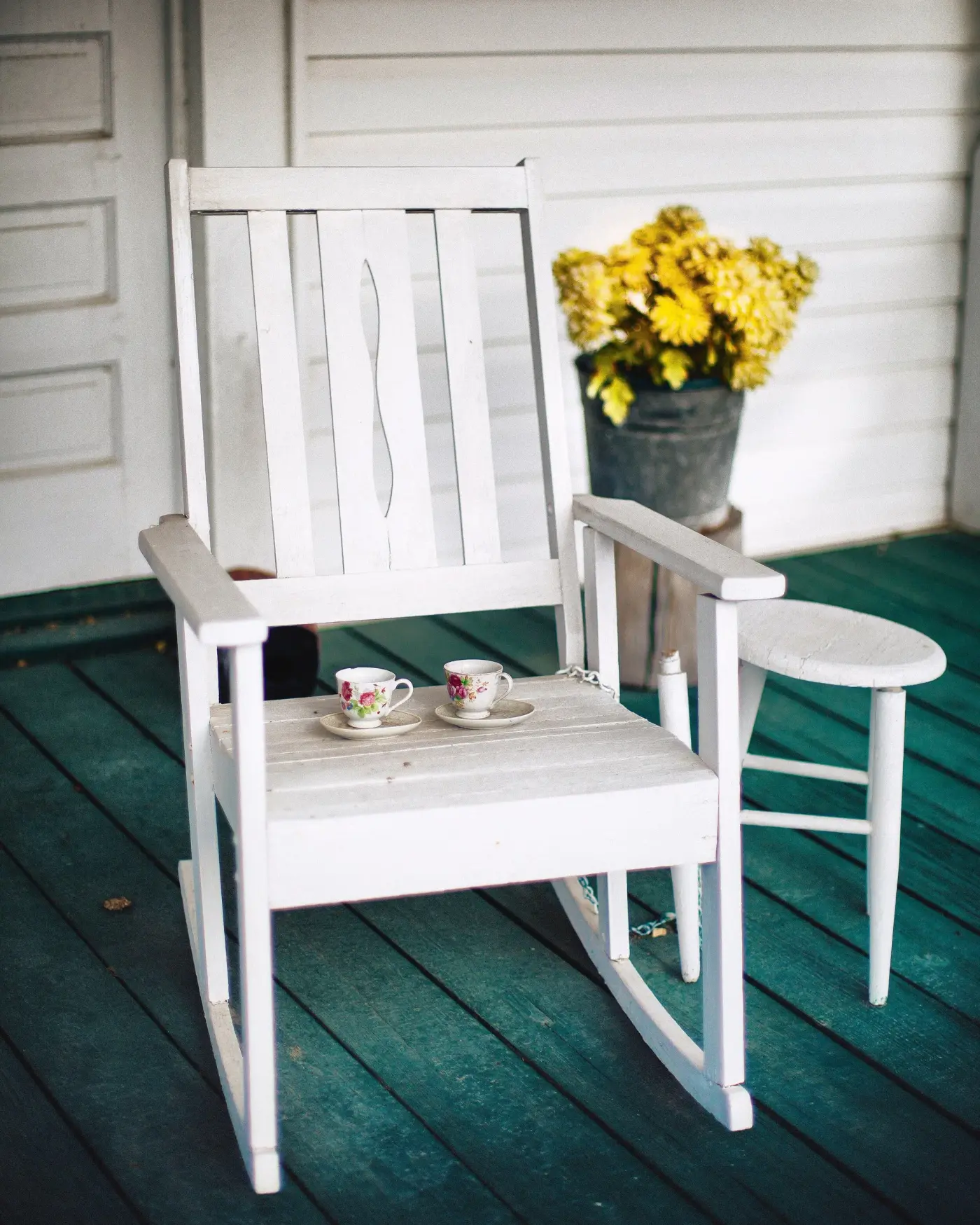 Rocking-chair blanc et tasses sur une véranda