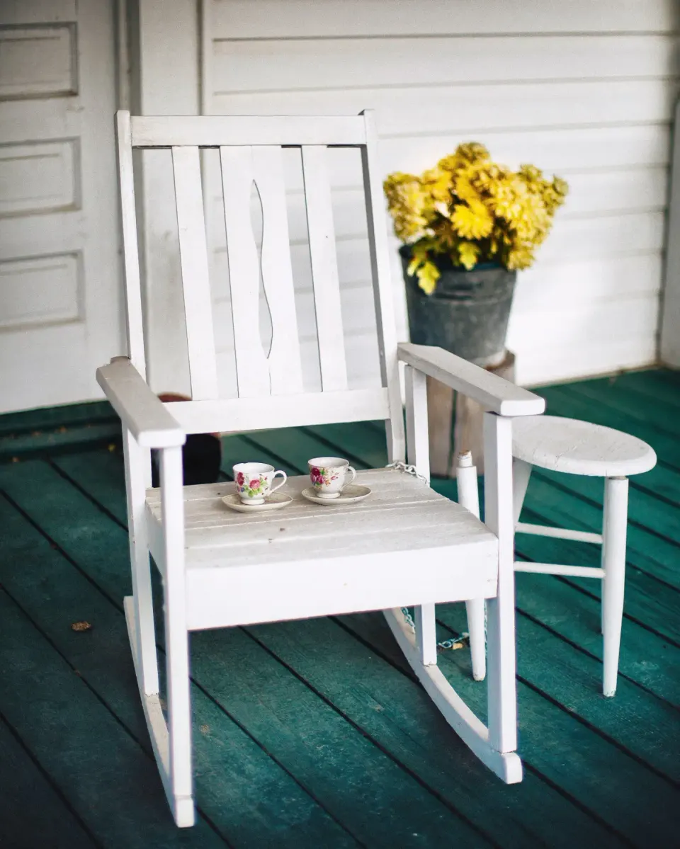 Rocking-chair blanc et tasses sur une véranda