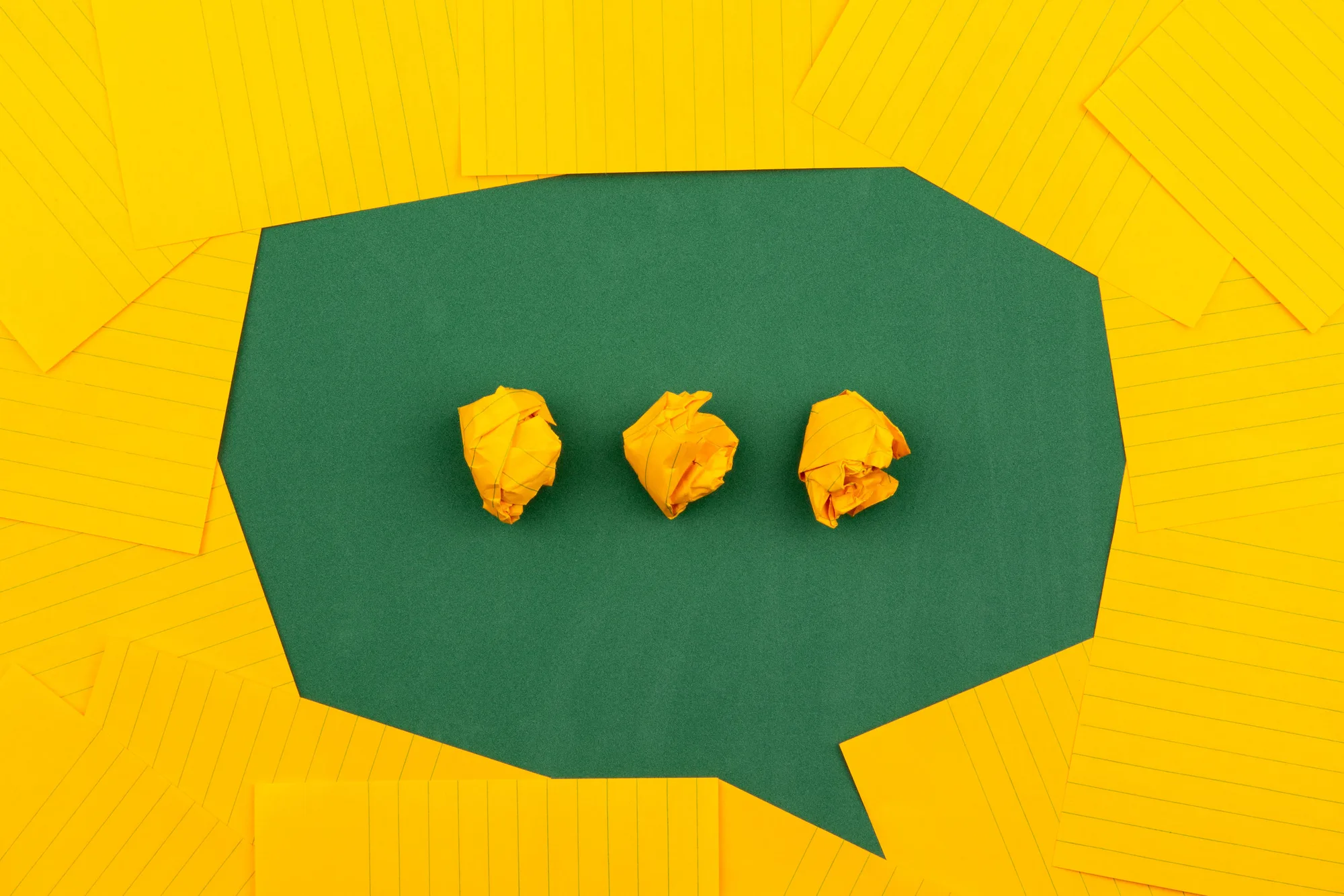 Bulle de dialogue verte et papiers jaunes froissés