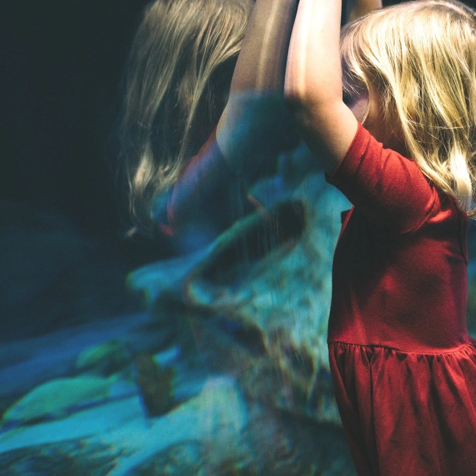 Fillette en robe rouge devant une vitre d'aquarium