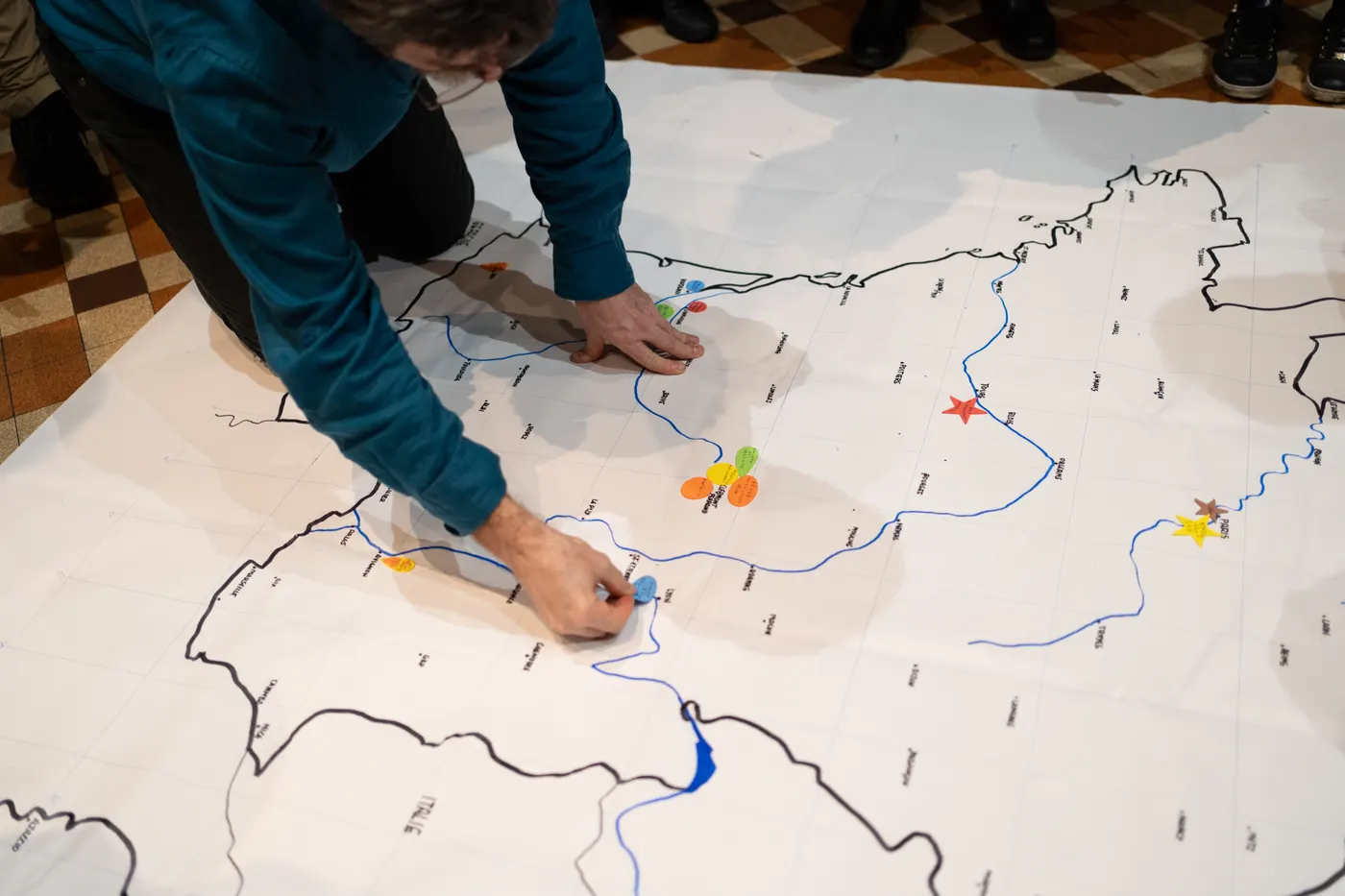 Homme agenouillé posant des pions sur grande carte
