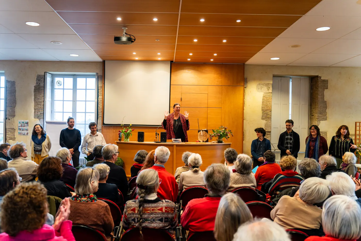 Conférencière devant une salle comble applaudissant