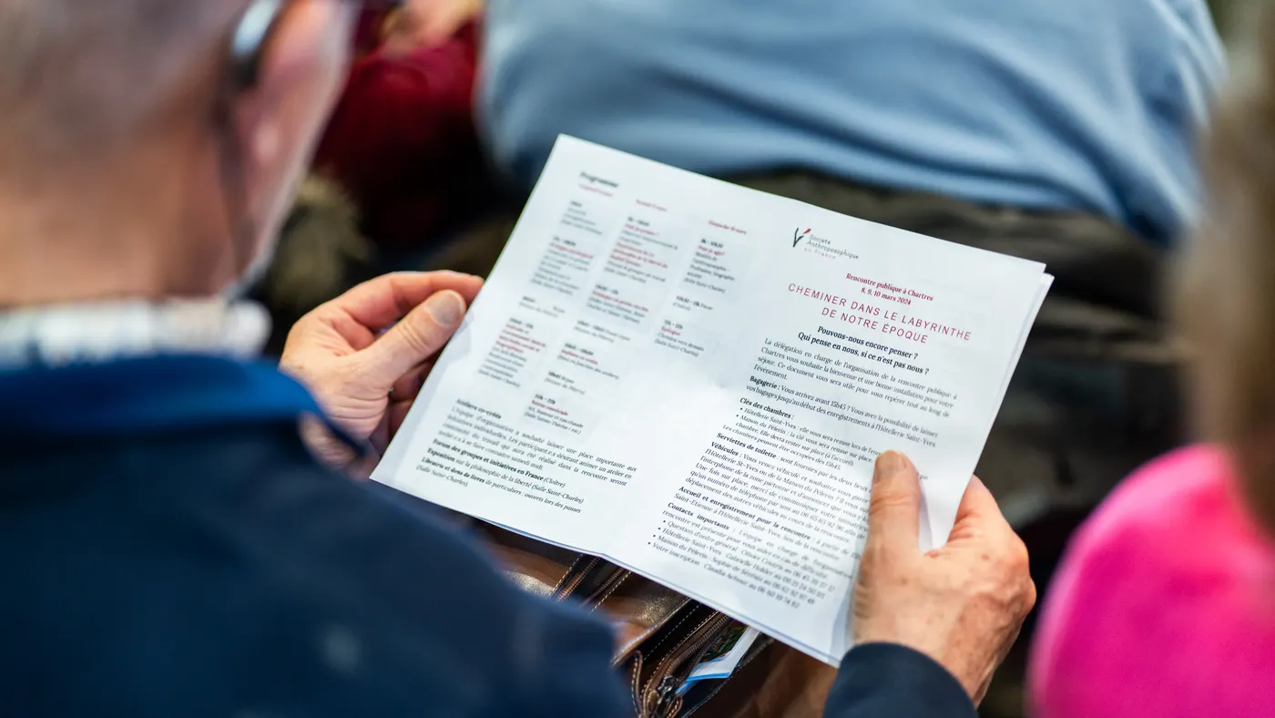 Personne lisant un programme imprimé en salle