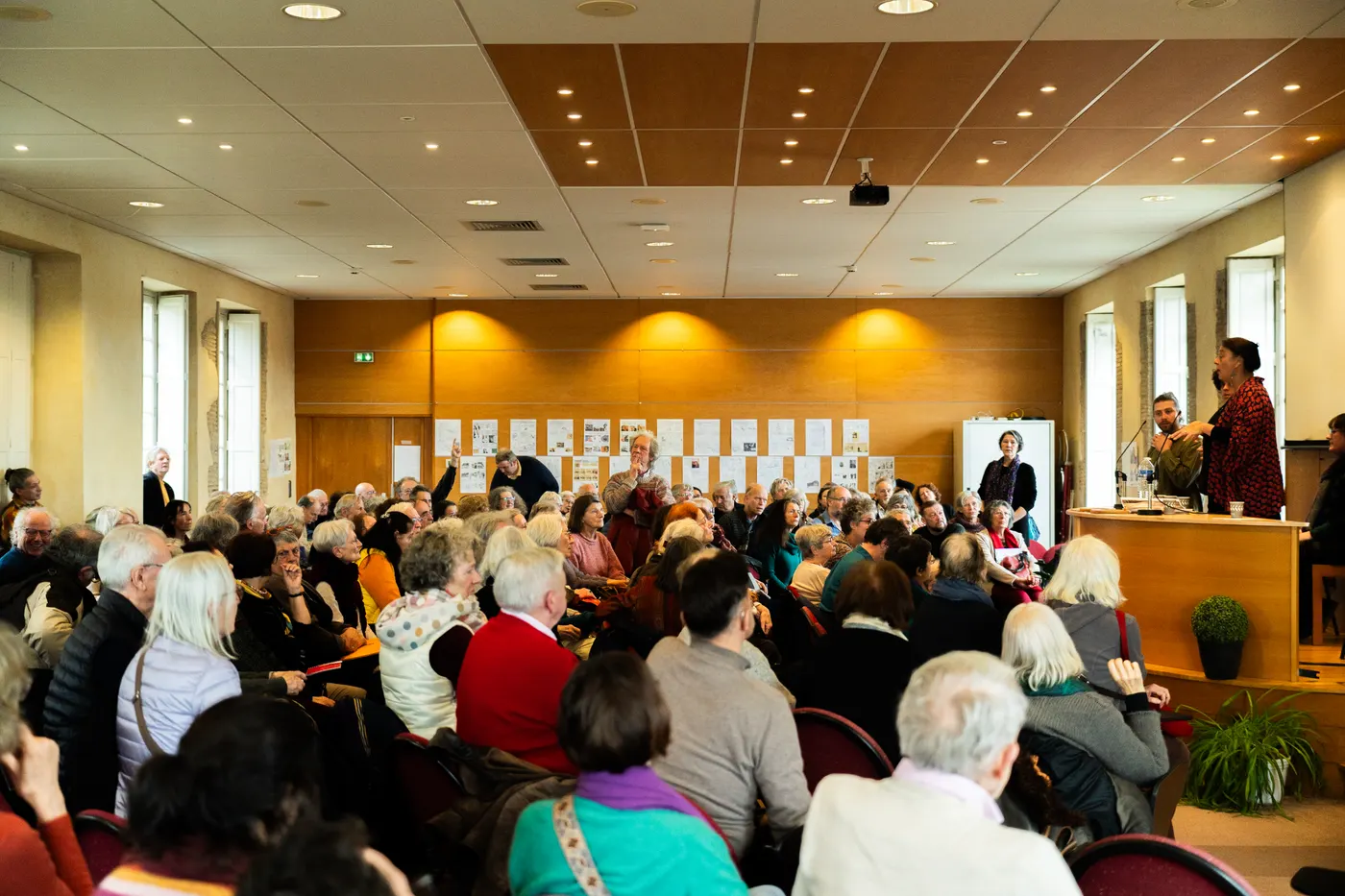 Salle de conférence comble avec intervenants au pupitre