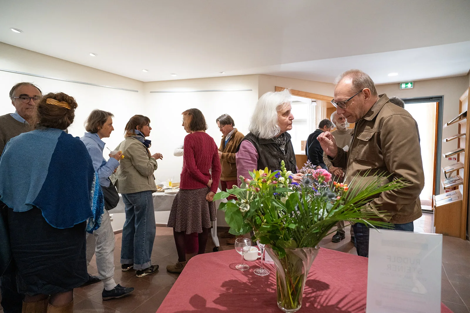 Personnes discutant lors d'un buffet, bouquet au premier plan
