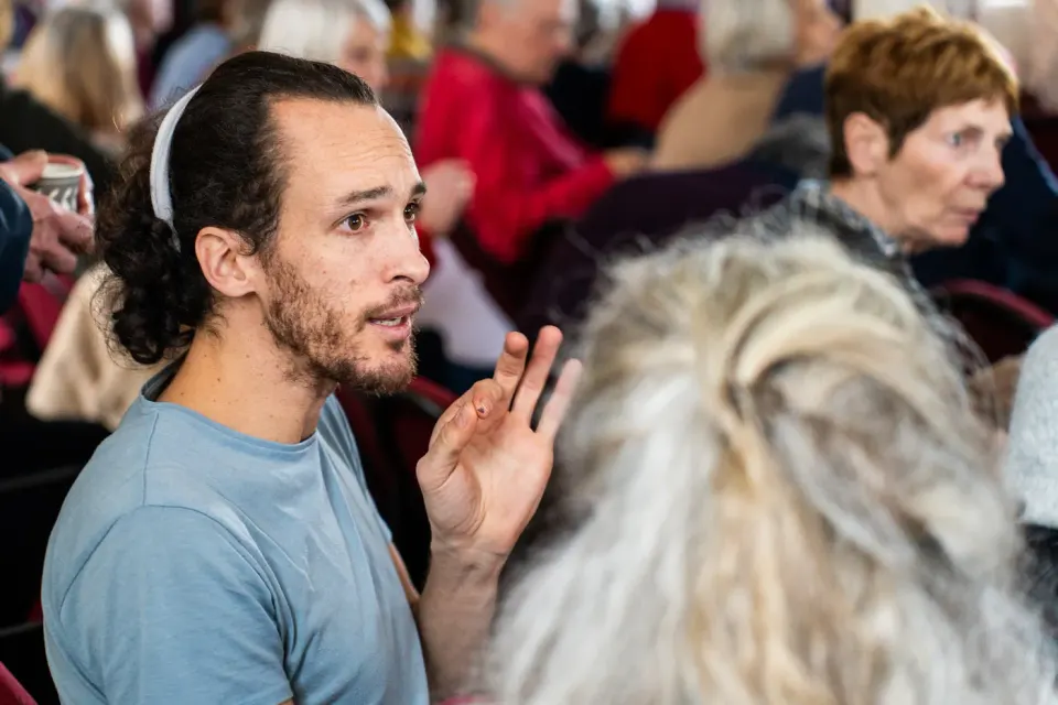 Jeune homme barbu s'exprimant dans une assemblée