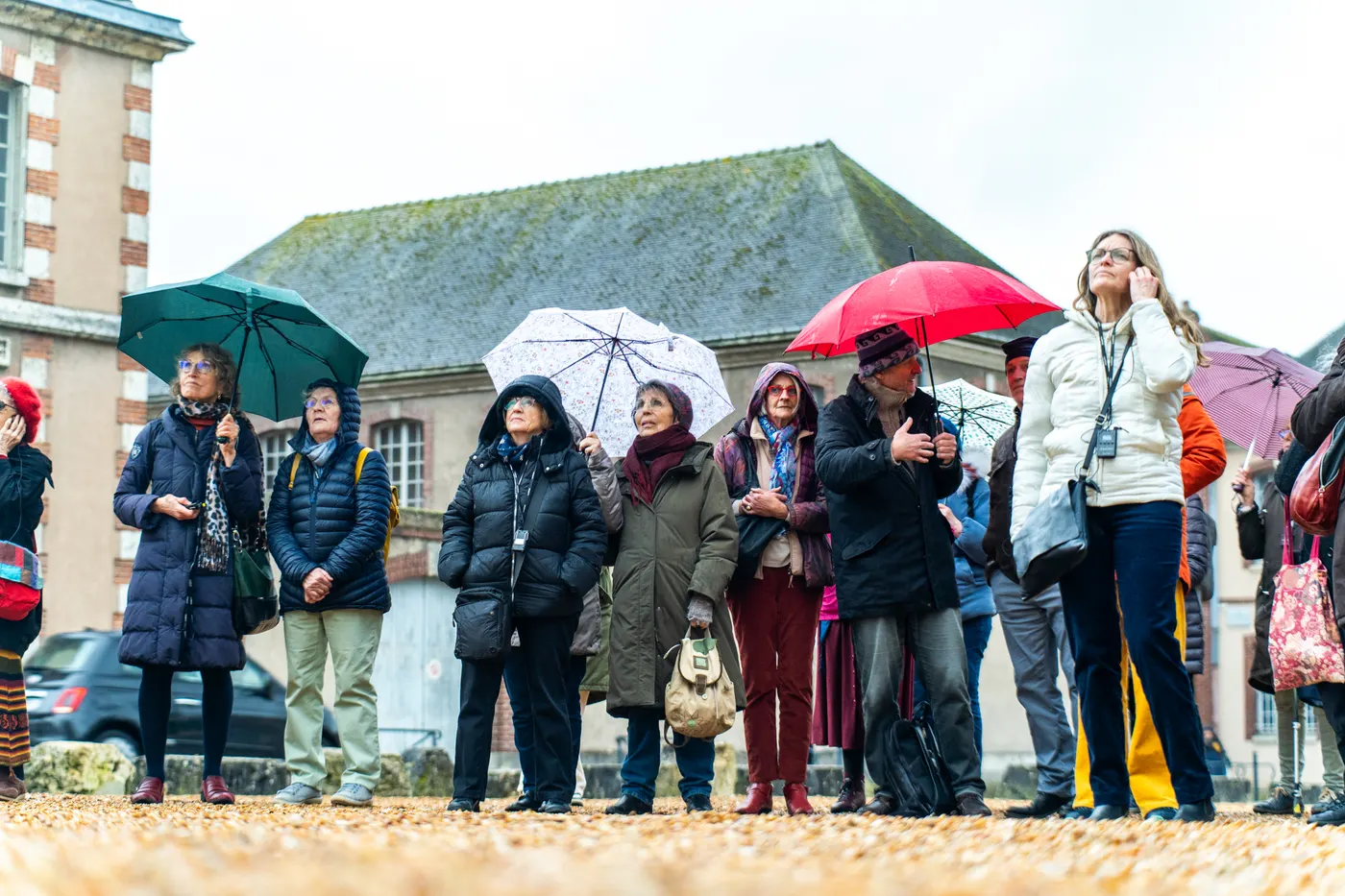 Groupe sous la pluie écoutant une visite guidée