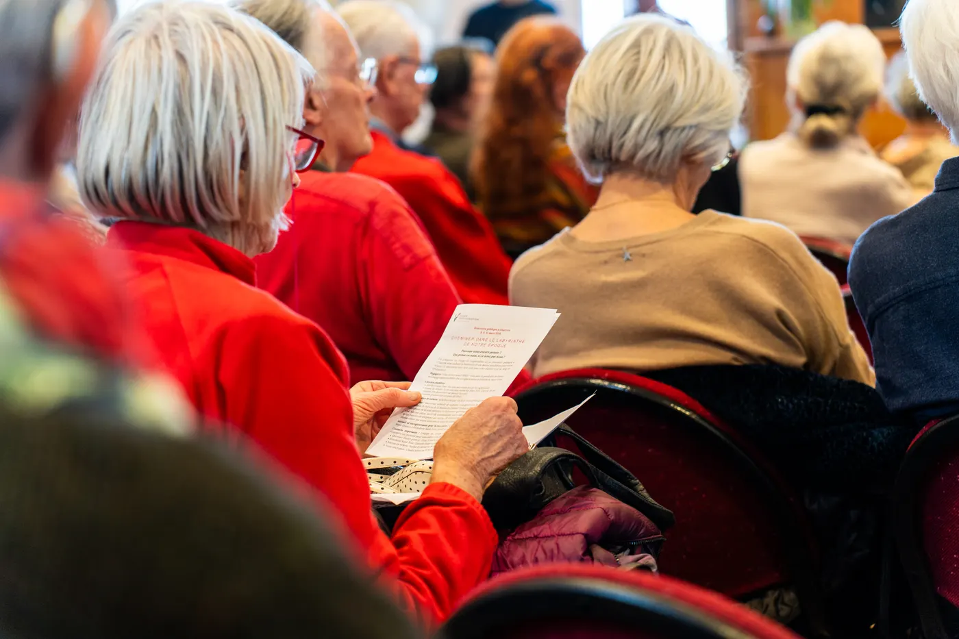 Spectatrice lisant un programme dans une assemblée