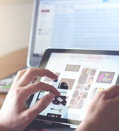 Mains utilisant une tablette devant un ordinateur portable